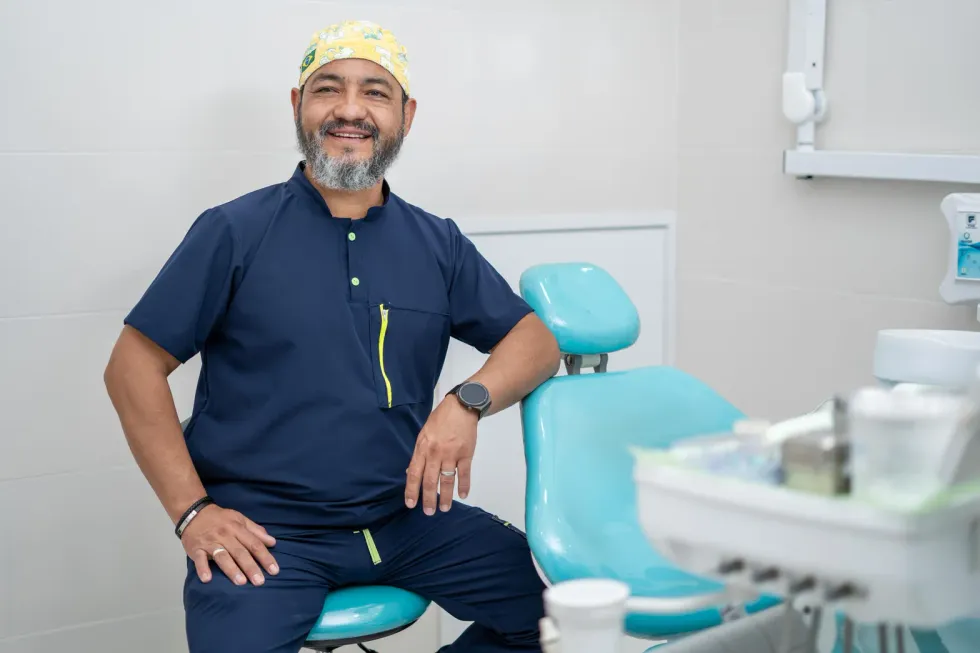 Dr. Cristián Romero sonriendo junto a la silla dental